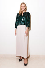 Load image into Gallery viewer, A model wearing a shiny emerald green lamé upper part with a nude crepe lower part dress, with a comfortable and elegant kaftan cut, side slits, and a front chest opening.