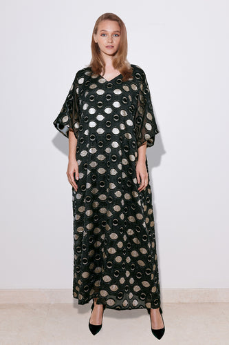 A model wearing a long, polka dot cream organza dress with a V-neck and wide bell-shaped sleeves, standing against a neutral background.