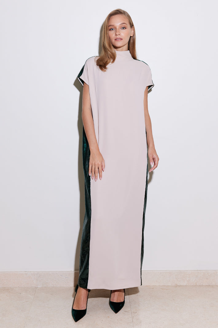 A model wearing a straight cut nude dress with a contrasting green lamé back panel, cap sleeves, high neck collar, and two back buttons.